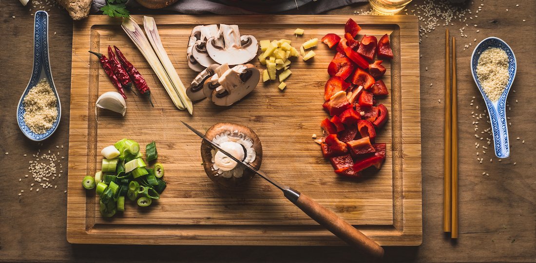 Copped vegetables ingredients for tasty vegetarian stir fry dishes on wooden cutting board with knife and chopsticks, top view. Asian cuisine. Healthy eating and food concept Nutritional Counselling